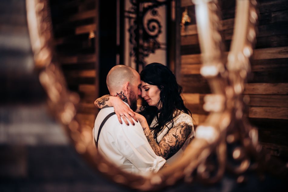 An intimate couple's portrait captured through a decorative frame with warm lighting.