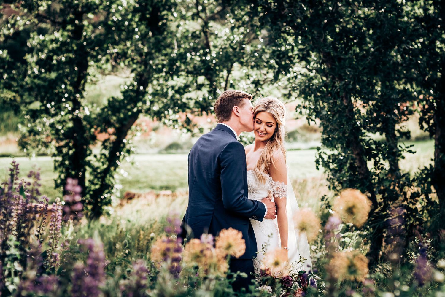 Intimate wedding moment captured in wildflower garden with natural lighting.