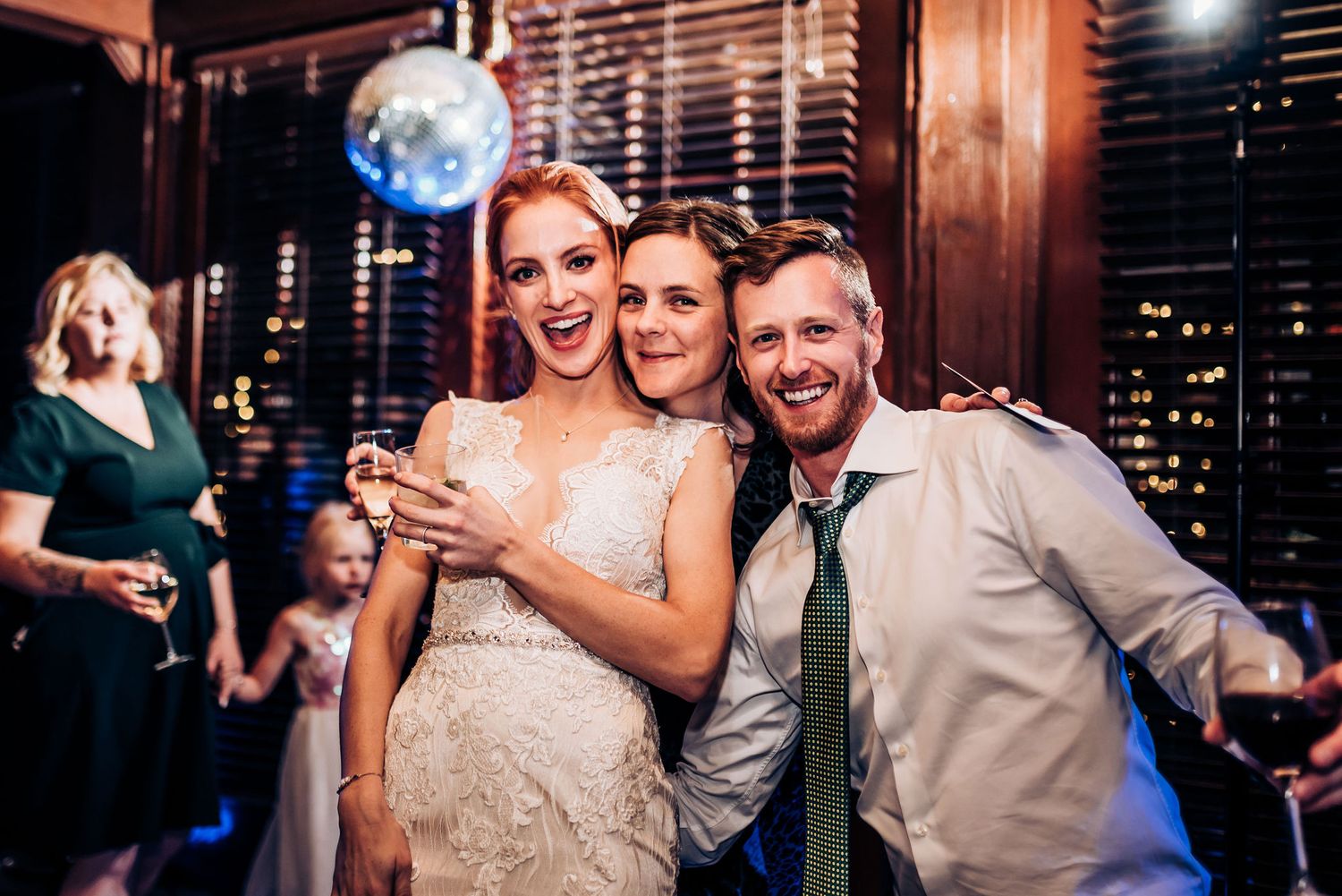 Party guests celebrate together under disco lights at an evening reception.
