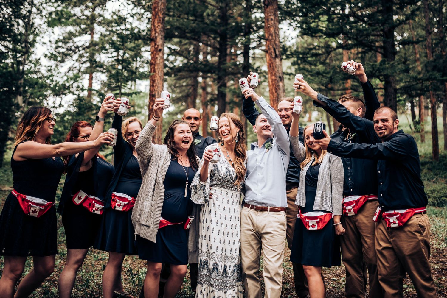 Wedding party shows off matching red underwear beneath formal attire in forest setting.