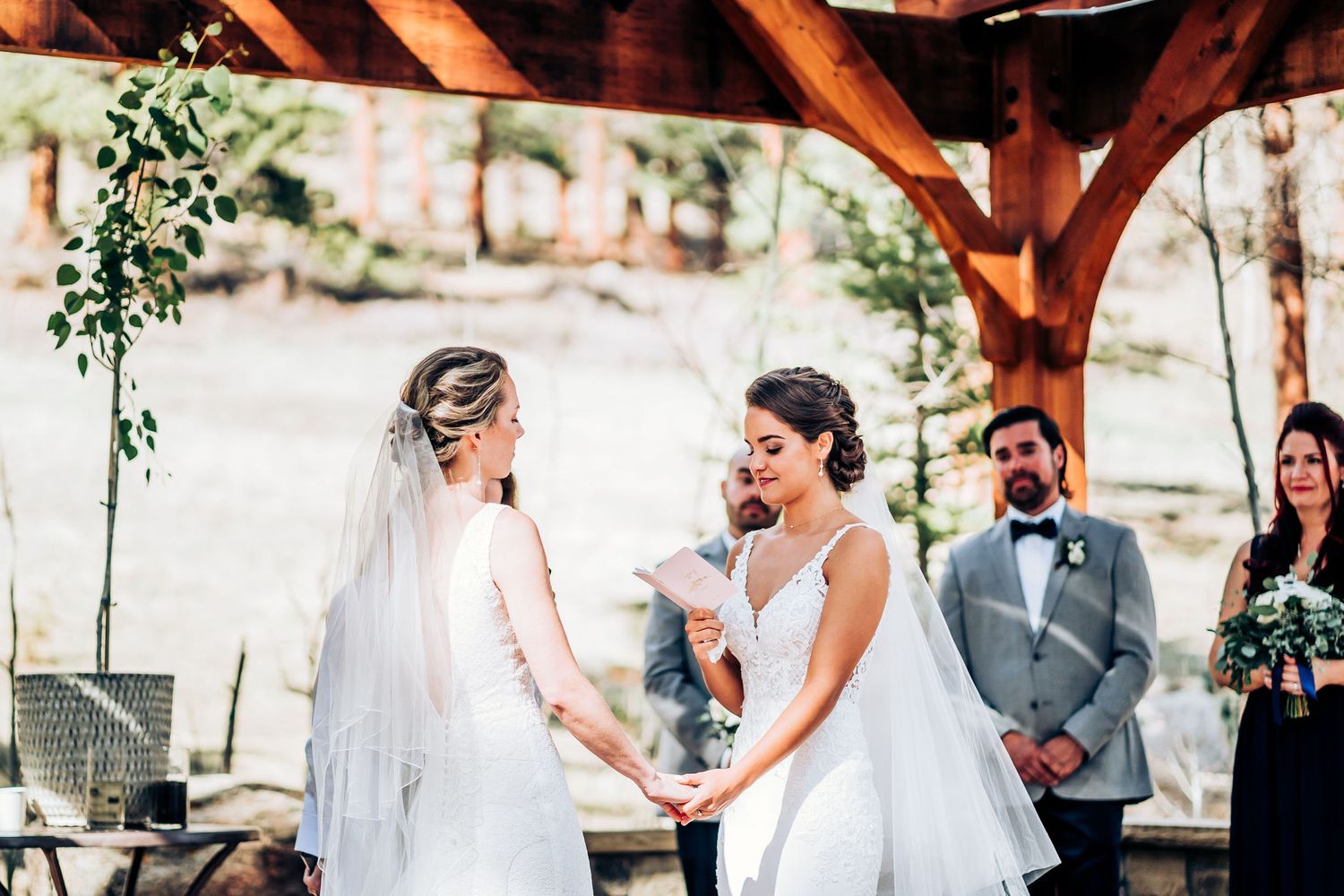 Emotional wedding ceremony moment under wooden pergola with greenery decorations.