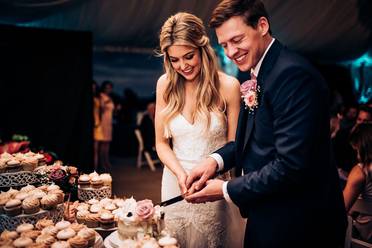 Couple serves desserts together at wedding reception sweets table.