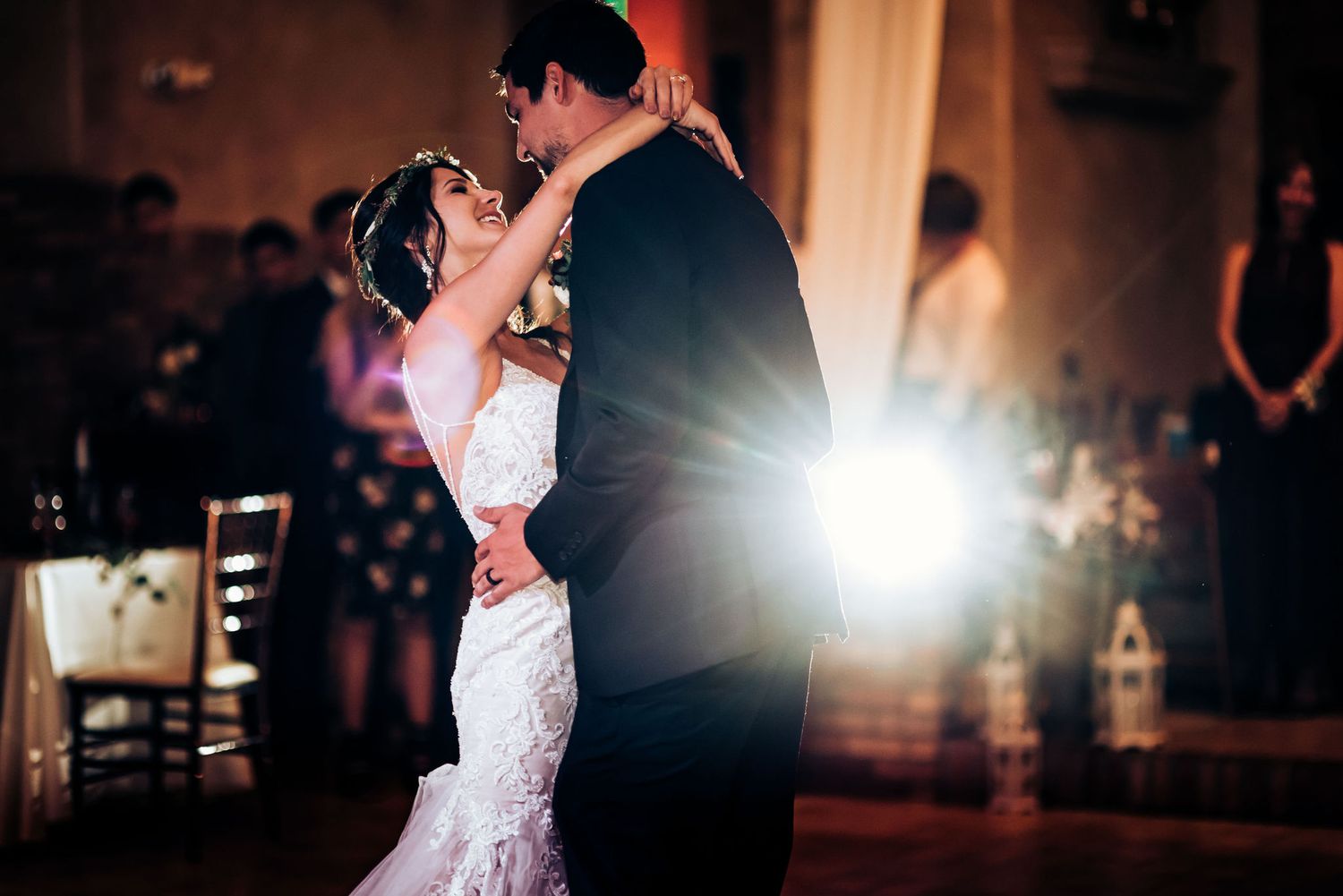 A romantic first dance moment captured with dramatic backlighting at an indoor wedding reception.