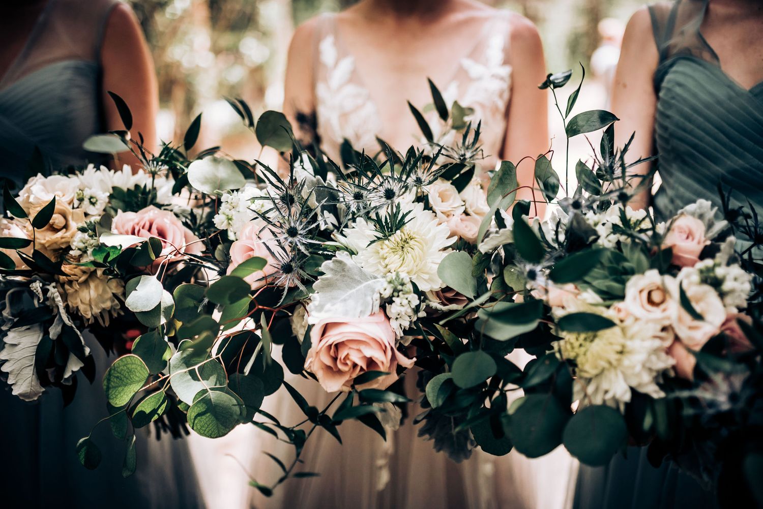 Close-up of wedding bouquets with pink roses, white flowers and eucalyptus greenery.
