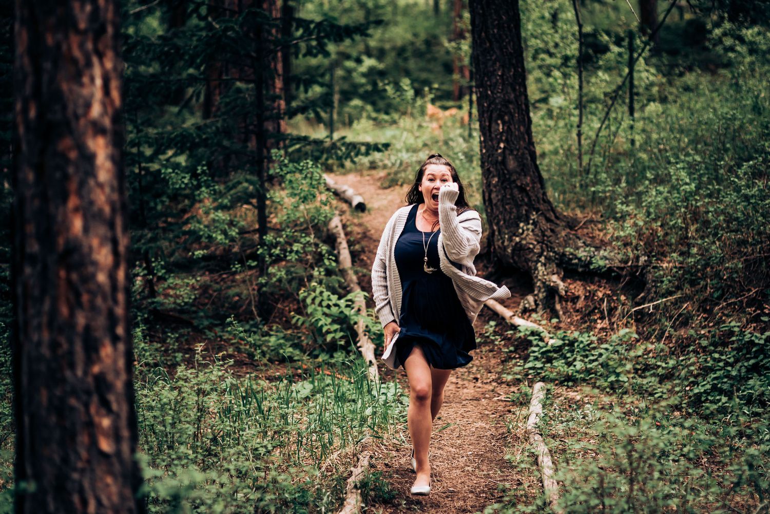 A runner in black athletic wear jogs along a scenic forest trail.