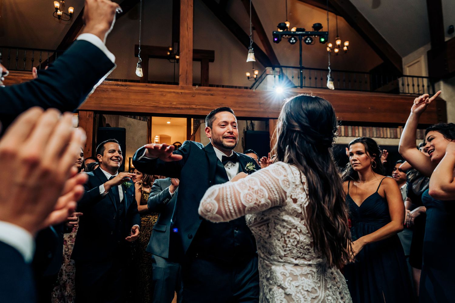 Wedding guests surround the dancing couple during a festive reception celebration.