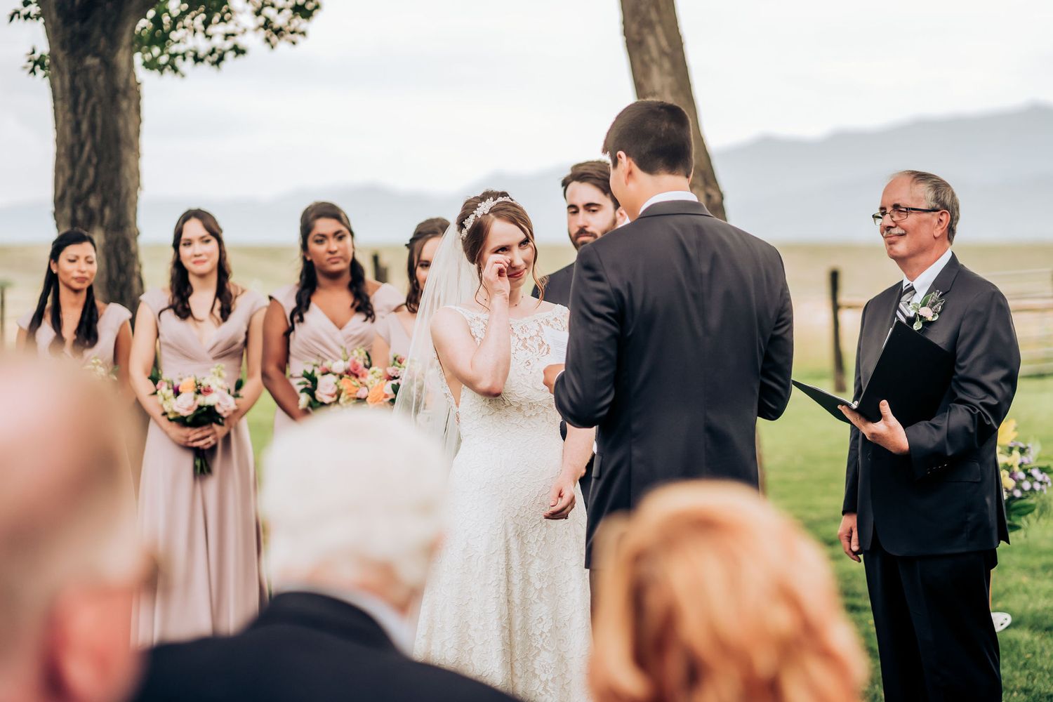 Couple exchanging vows at mountain wedding with bridal party and guests in attendance.