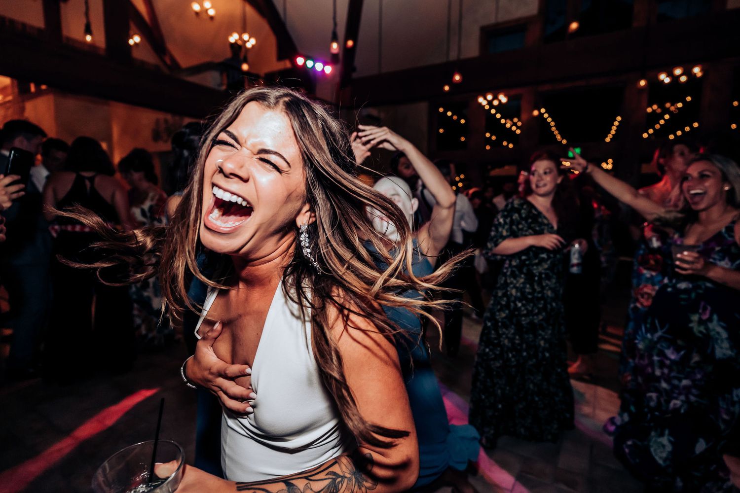 Woman dancing joyfully with hair flying at a lively wedding reception party.