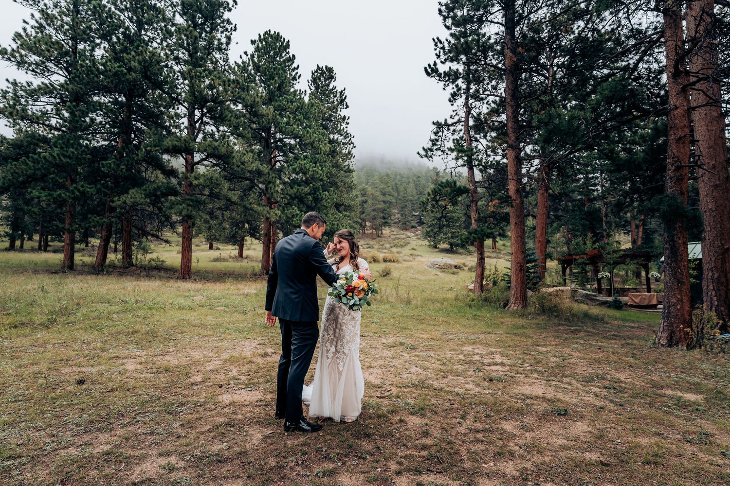 Romantic moment between newlyweds in mountain pine forest clearing.
