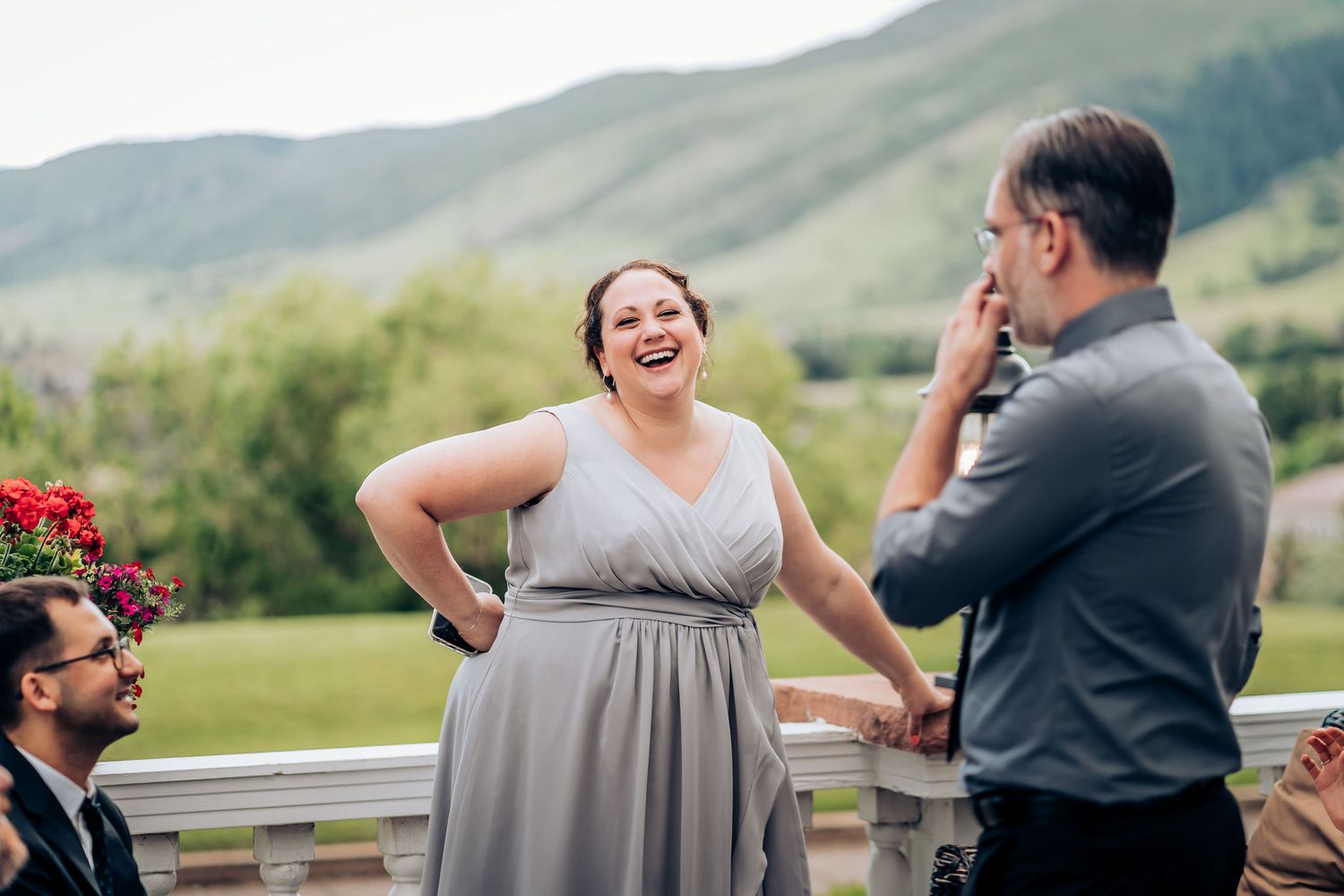 Candid moment of laughter shared during outdoor wedding celebration with mountain backdrop.