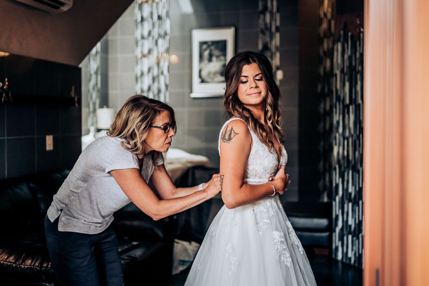 A wedding dress fitting moment captured as final adjustments are made in an intimate indoor setting.