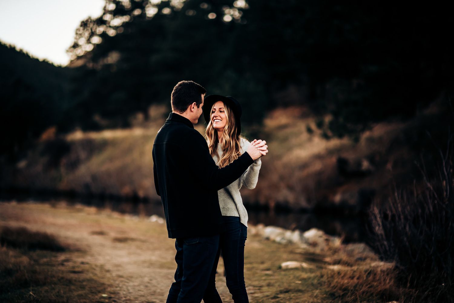 Couple dancing together on mountain trail during golden hour.