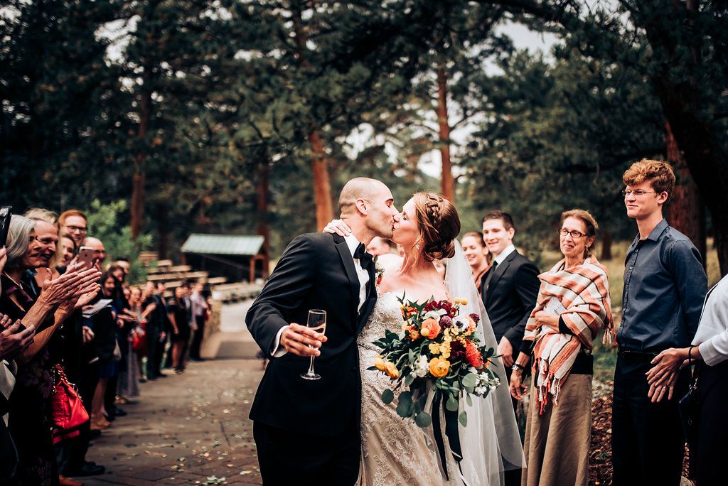 Outdoor wedding celebration with guests cheering during a forest ceremony.