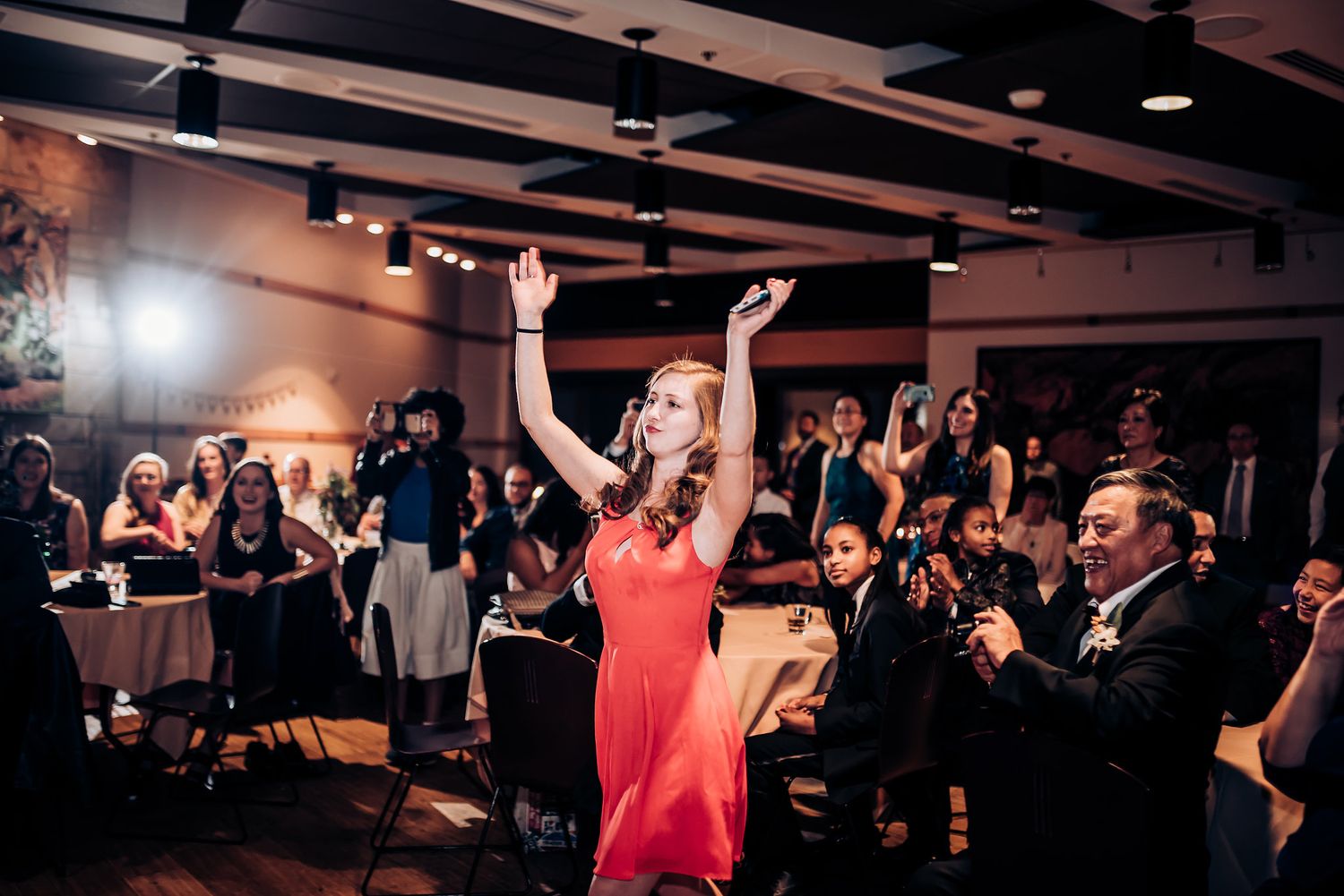 Wedding reception guests dance and celebrate under dramatic indoor lighting.