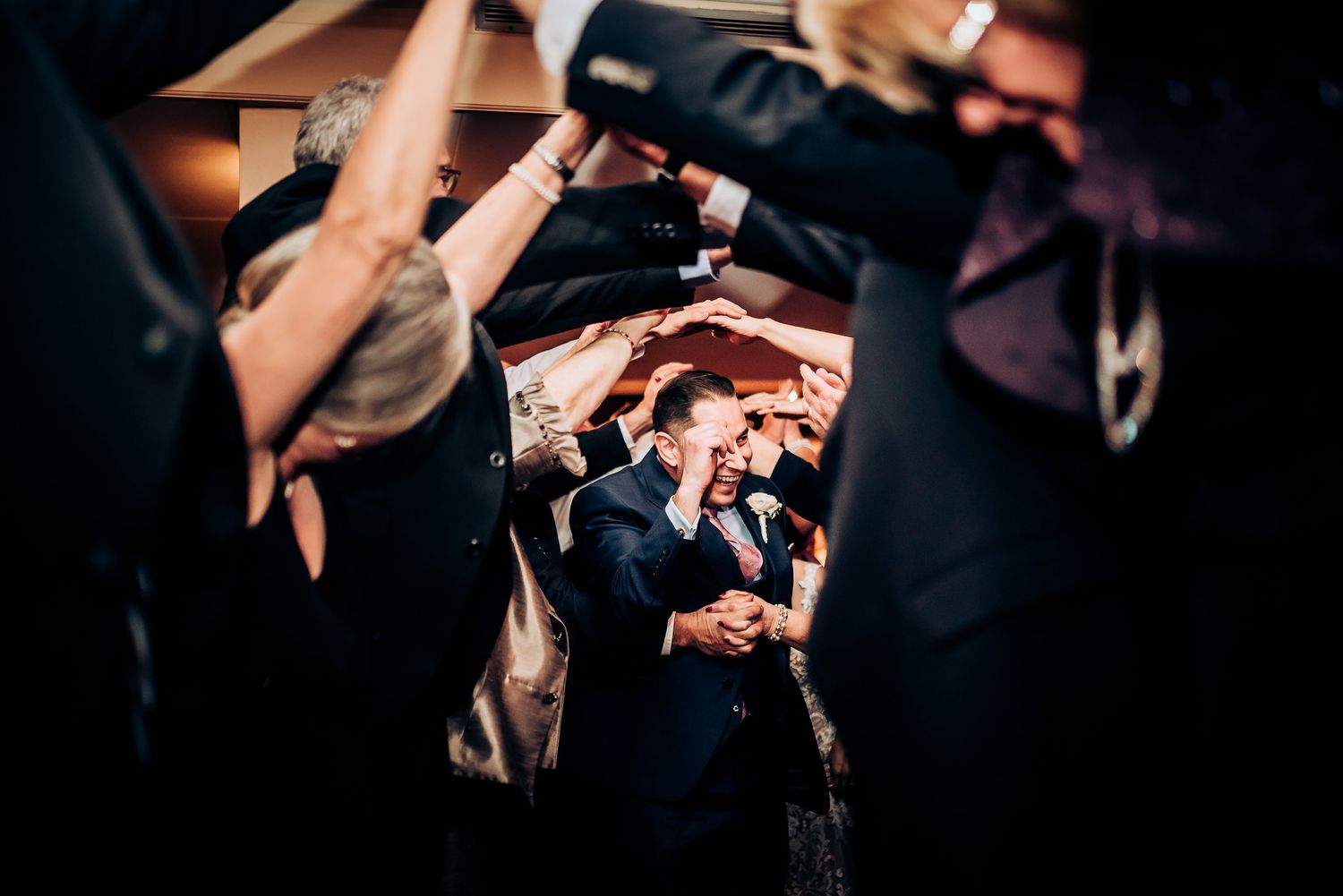 Dance floor celebration captured through crowd with camera flash lighting.