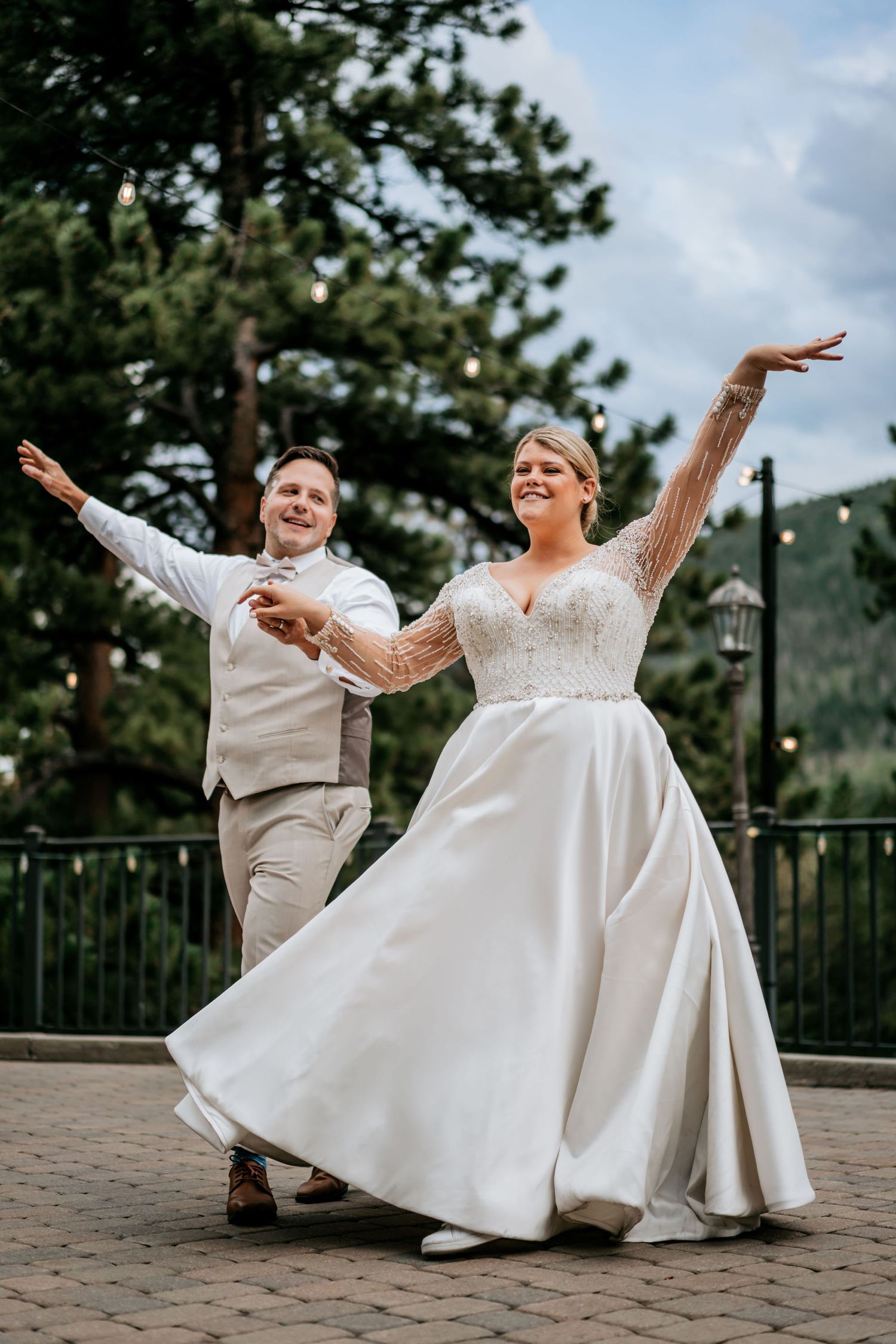 A joyful couple dances and twirls on an outdoor terrace during their wedding celebration.