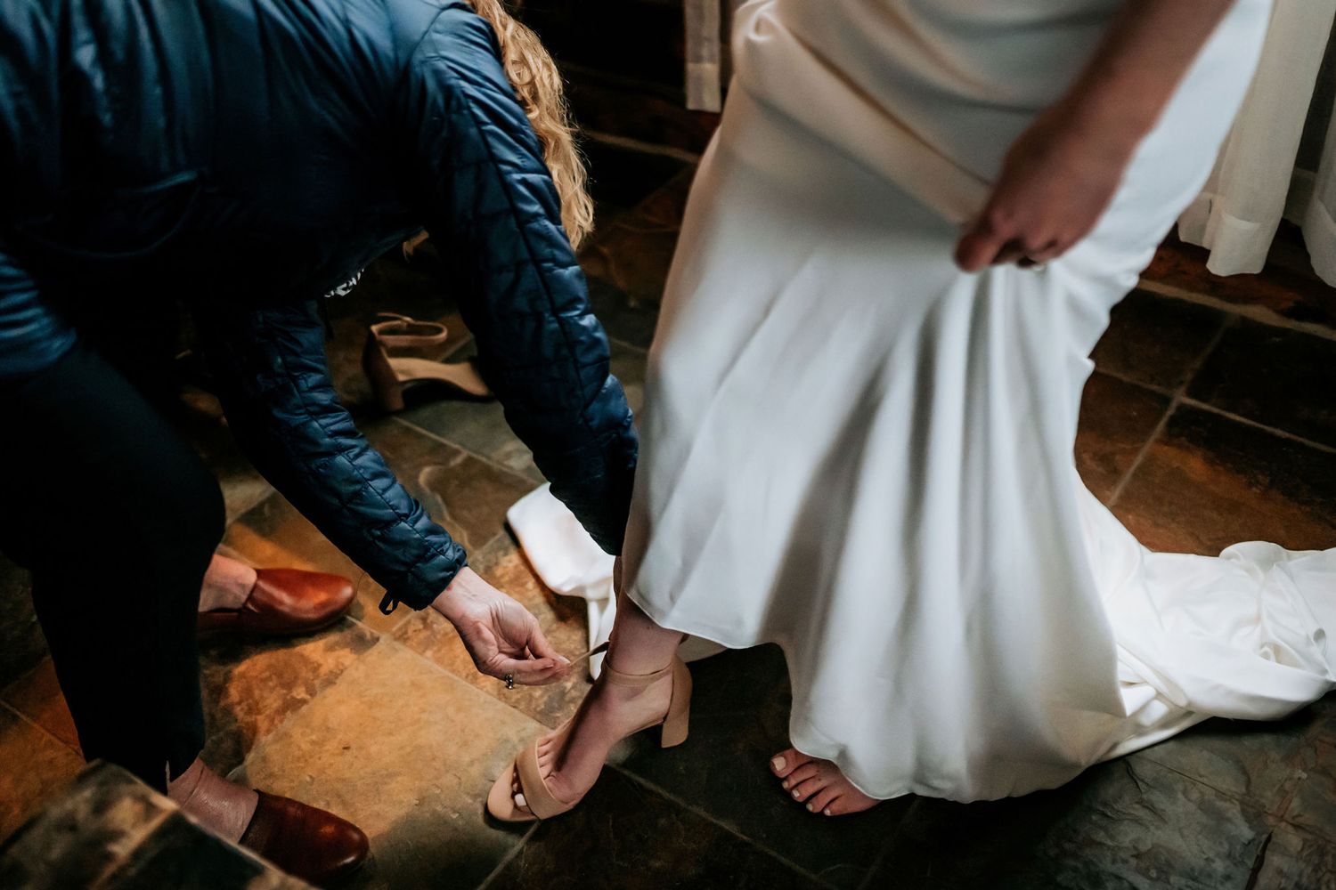 Close-up shot of someone adjusting wedding shoes on hardwood floor.
