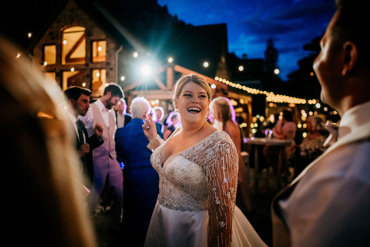 Guests enjoying an outdoor evening wedding celebration under string lights.