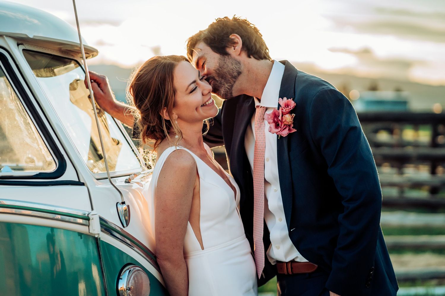 Romantic moment shared near a vintage turquoise car in a rustic outdoor setting.