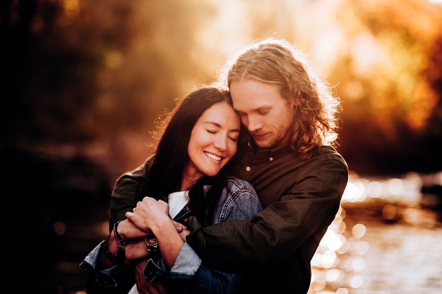 Couple sharing an intimate embrace during golden hour sunset by a stream.