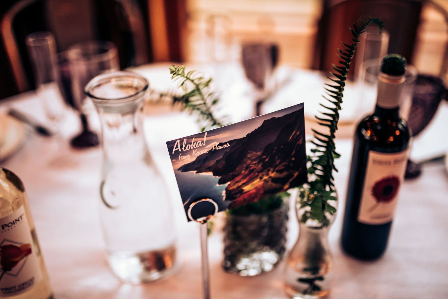 Wedding table setting with vintage travel postcards and wine bottles as decorative elements.
