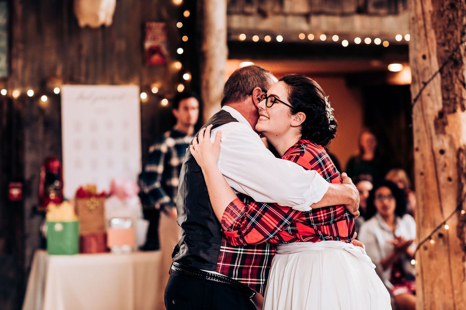 Couple embracing during dance at rustic venue with string lights.