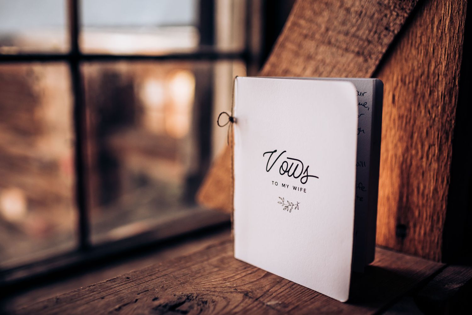 An elegant wedding invitation book displayed on a rustic windowsill.