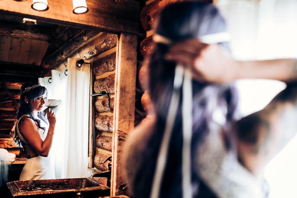 Someone looking out a cabin window during wedding preparations.