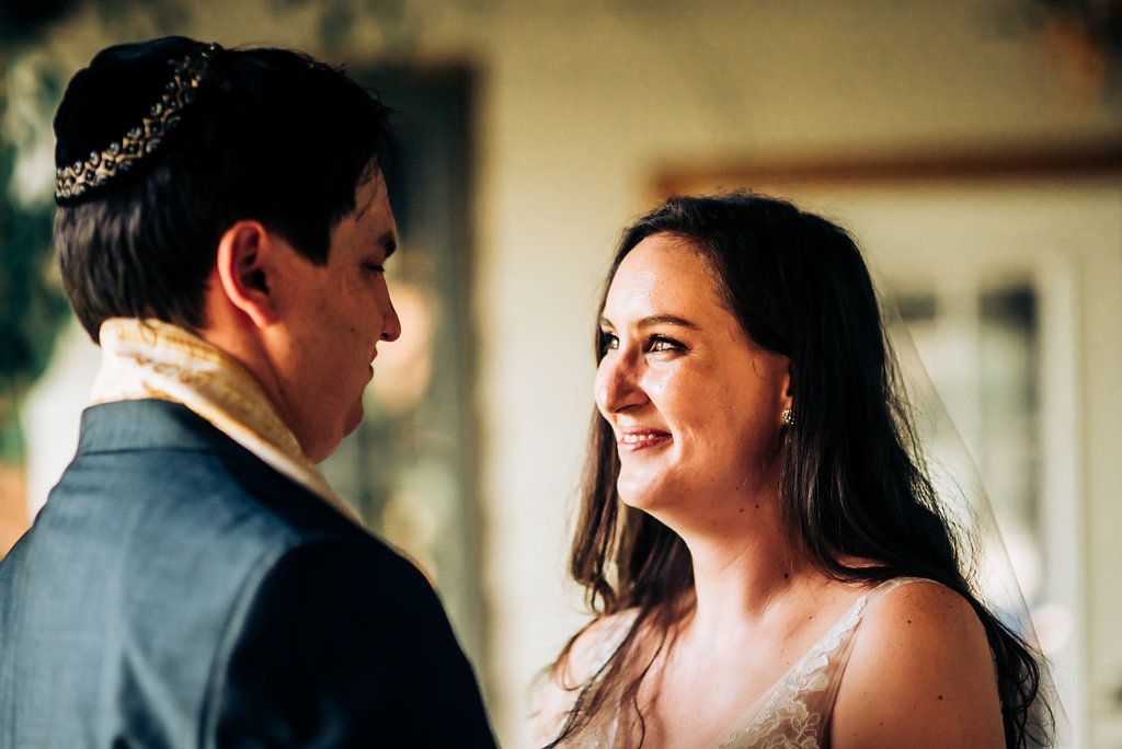 A couple shares an intimate moment during their wedding ceremony while exchanging loving glances.
