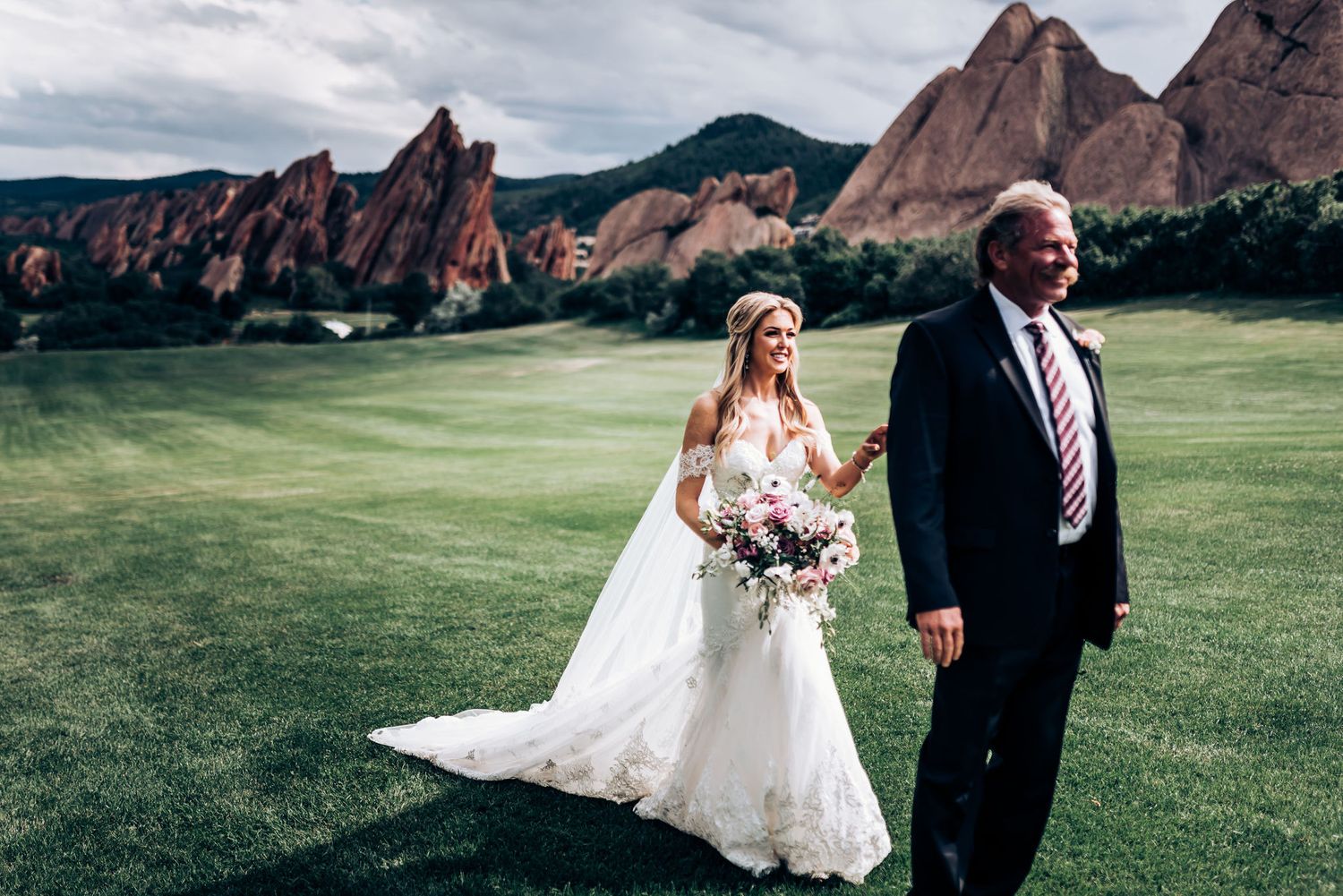 Wedding couple stands in front of dramatic red rock formations at Garden of the Gods.