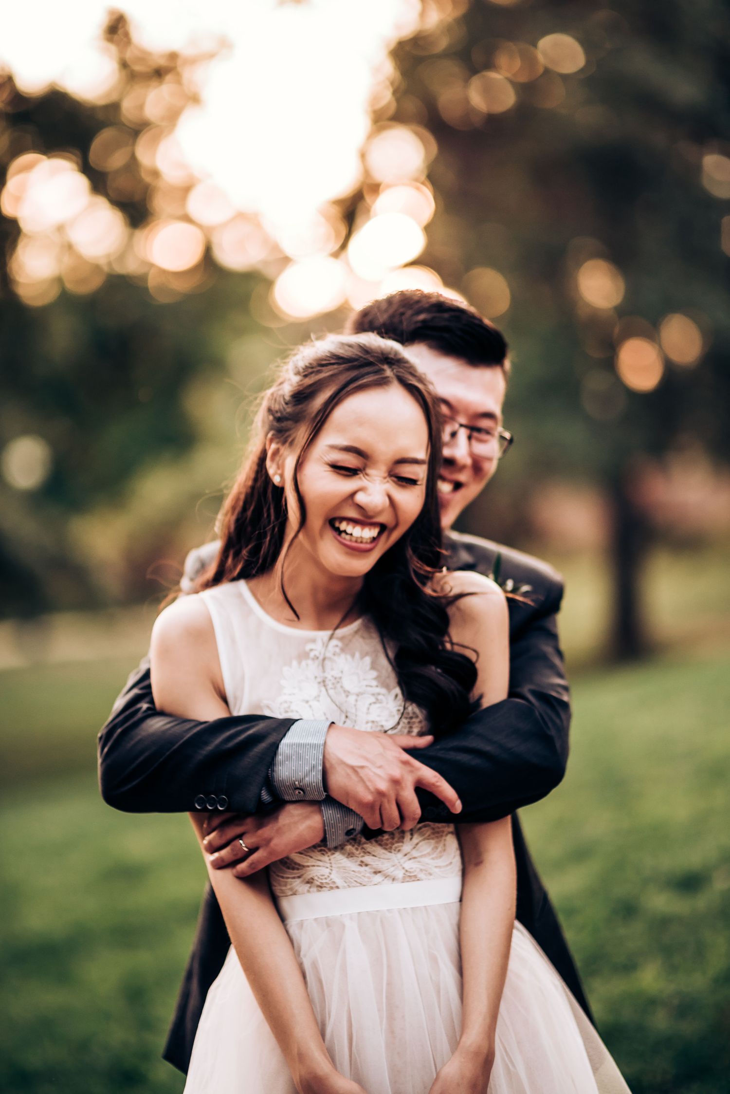 Romantic couple shares laughter during sunset engagement photoshoot in a park.