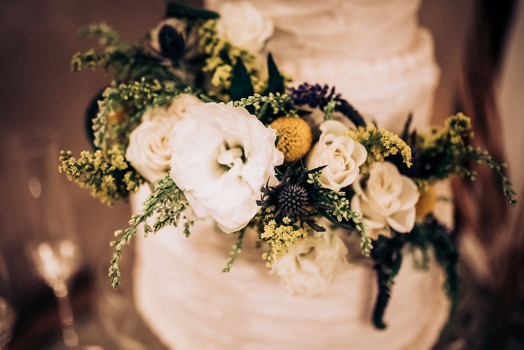 Close up of fresh floral decoration on wedding cake with white and yellow roses.