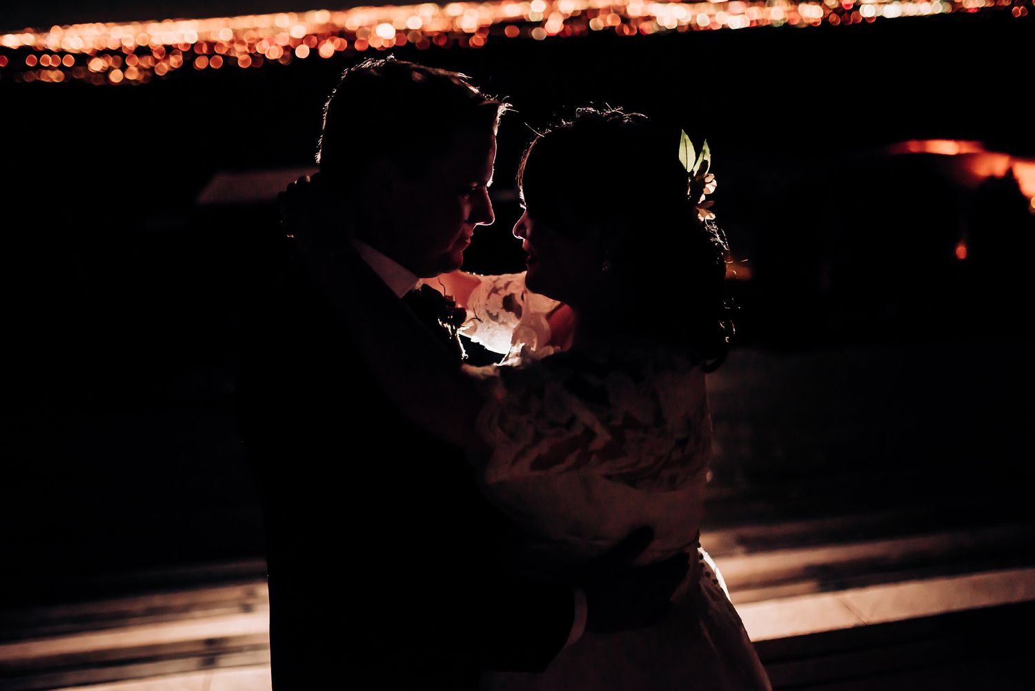 Intimate silhouette portrait with city lights glowing in background at night.
