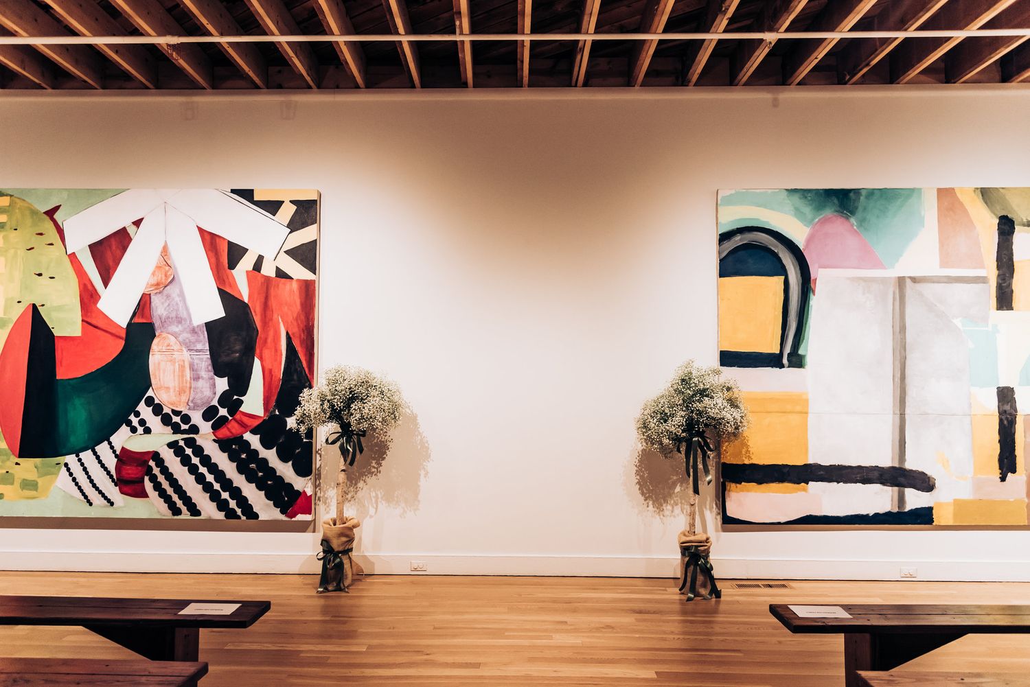Modern art gallery wall with abstract paintings and floral arrangements.