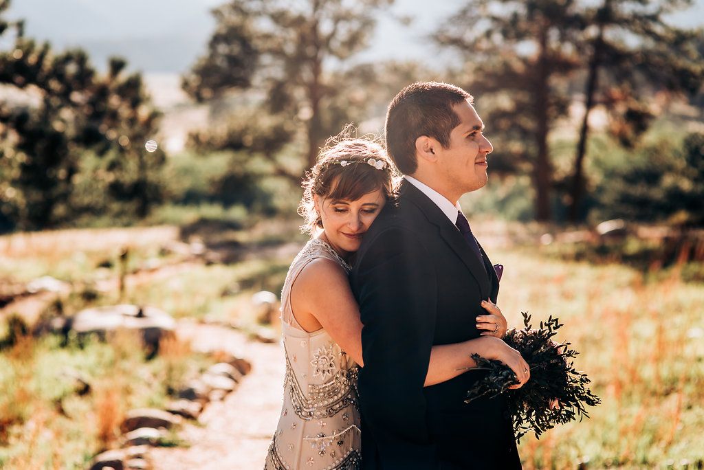Intimate wedding moment captured on mountain trail with natural scenery.
