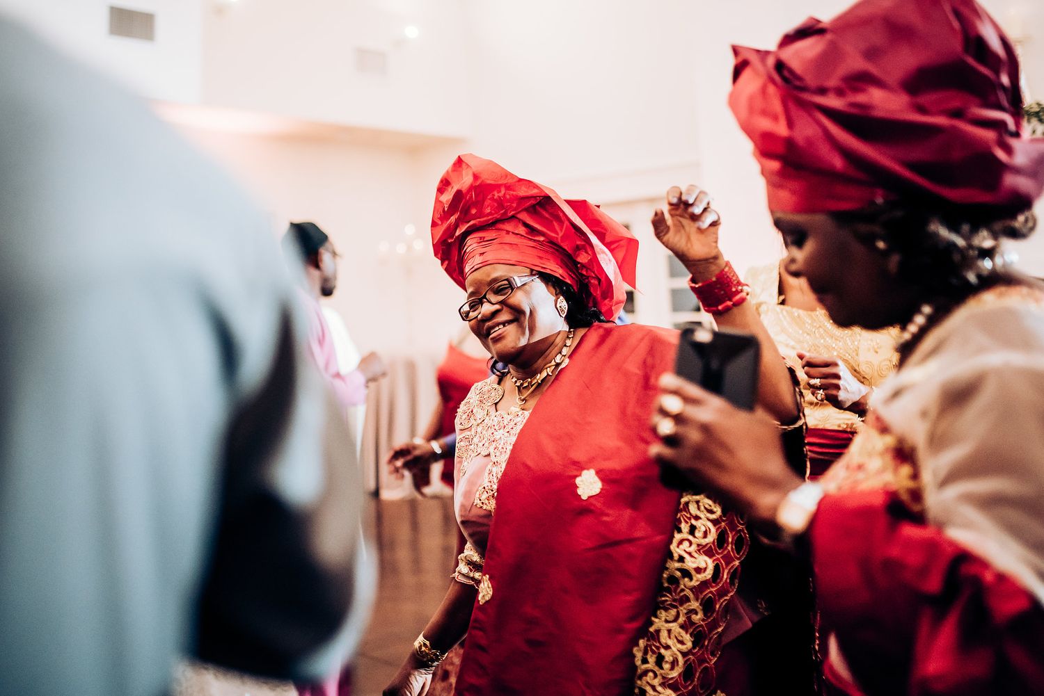 Wedding guest in vibrant red traditional dress dances joyfully during celebration.