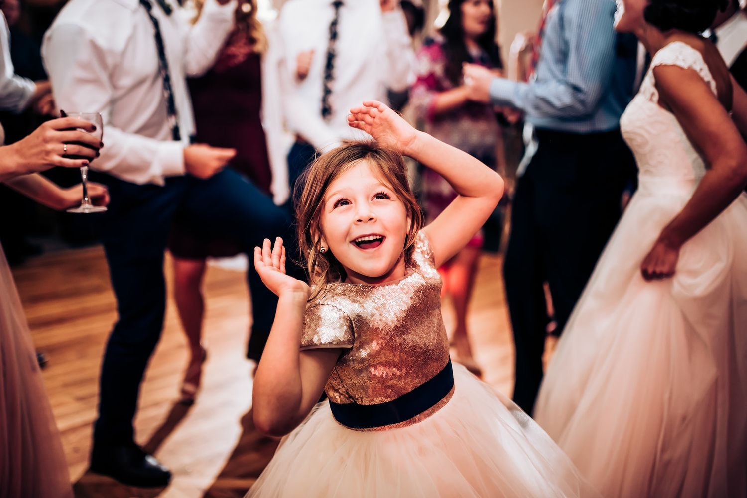Young girl in a sparkly tulle dress dances joyfully at a celebration.
