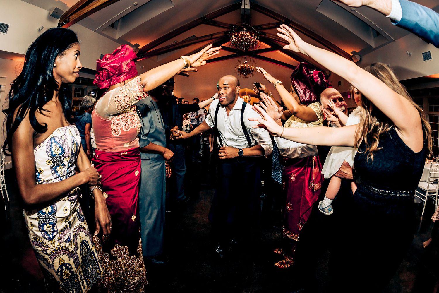 Party guests create a festive dance tunnel with raised arms at a celebration.