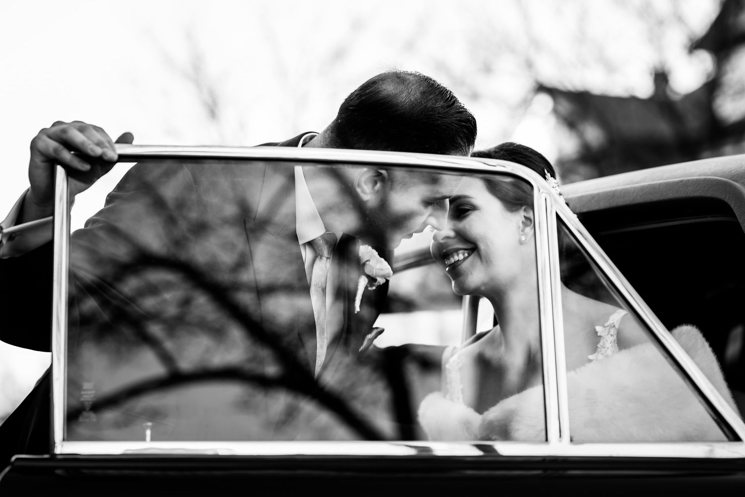 Black and white artistic wedding photo framed through car window.