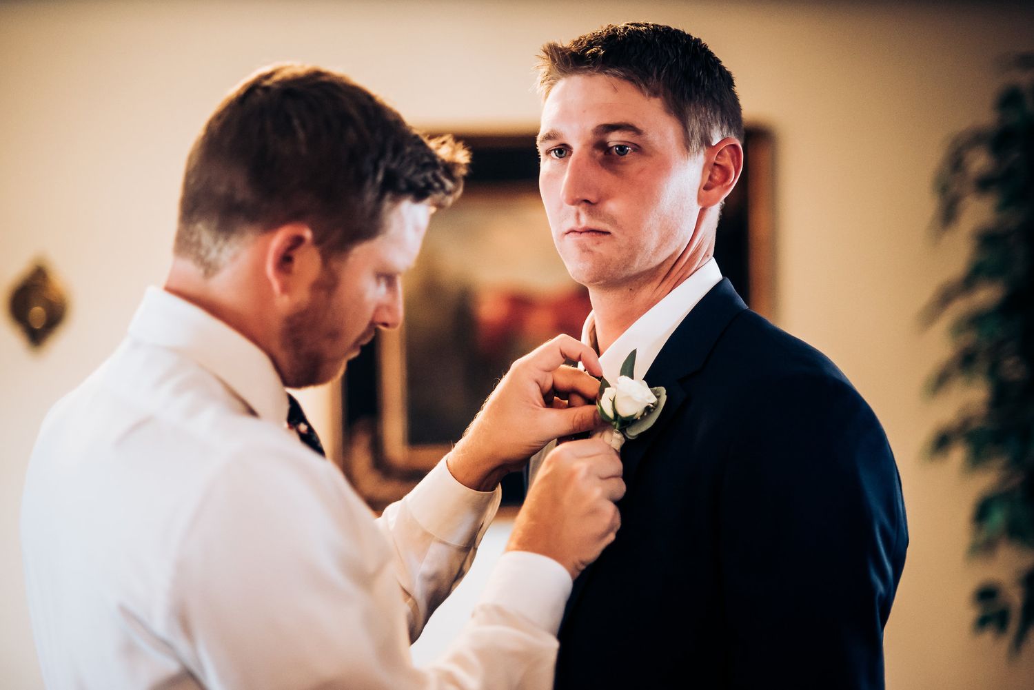 Formal preparation moment as boutonniere is pinned on suit.