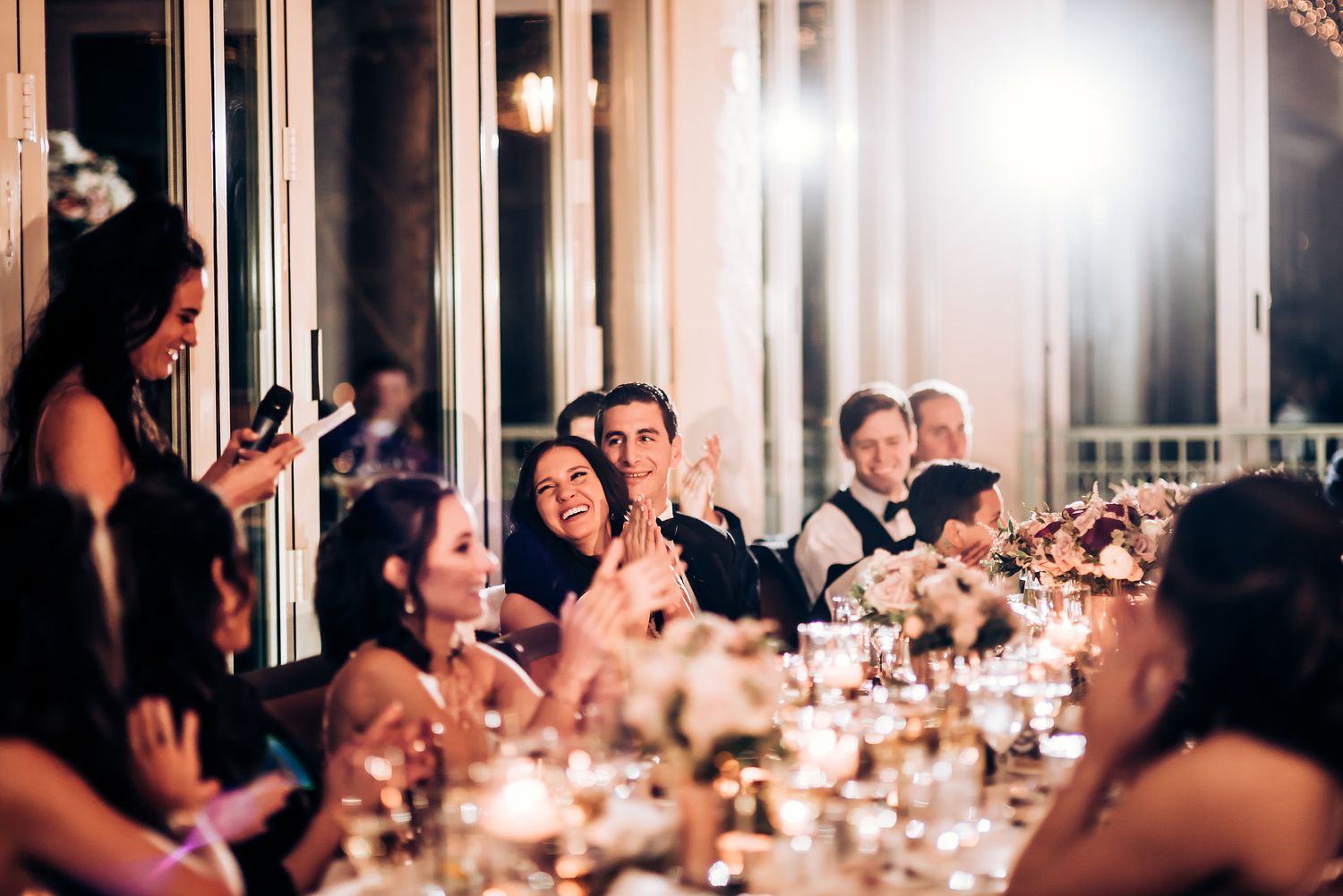 Candlelit wedding reception dinner with guests enjoying speeches and conversations.