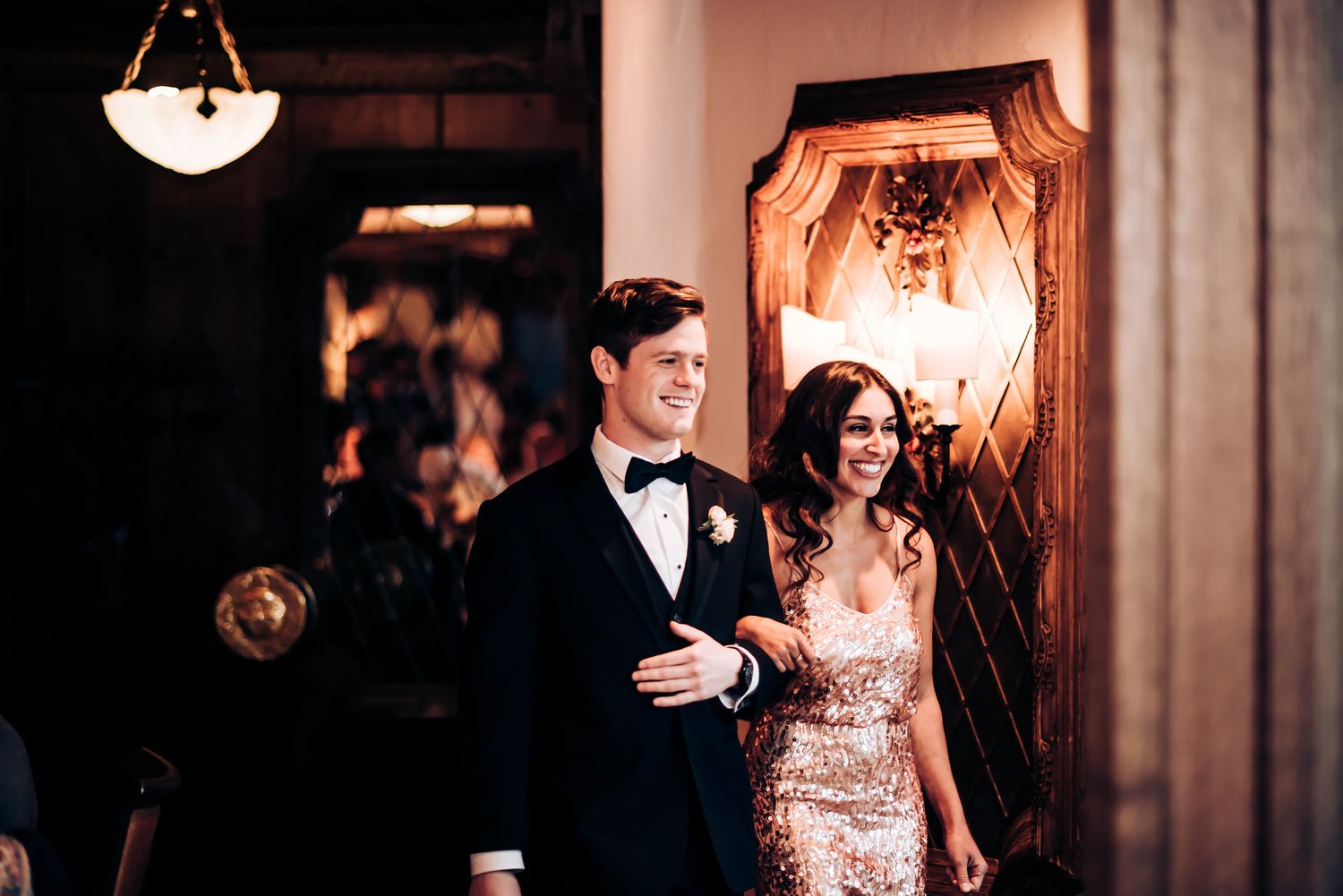 Couple making their entrance through an ornate doorway at an elegant venue.