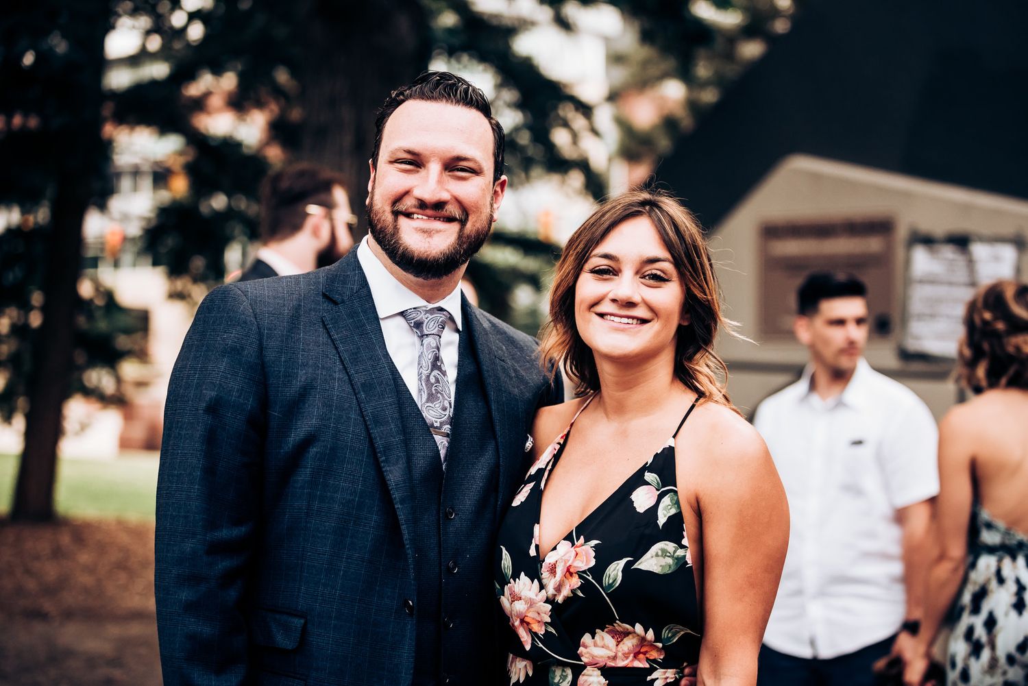 A couple in formal attire smiles at a wedding reception.