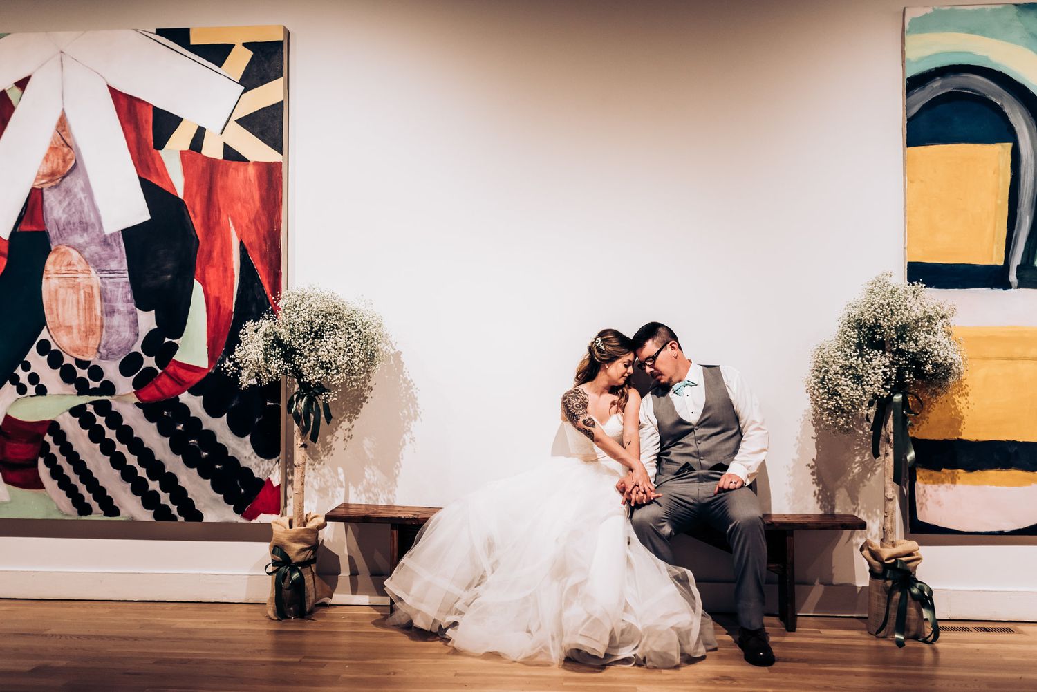 A couple sharing an intimate moment in an art gallery with floral arrangements.