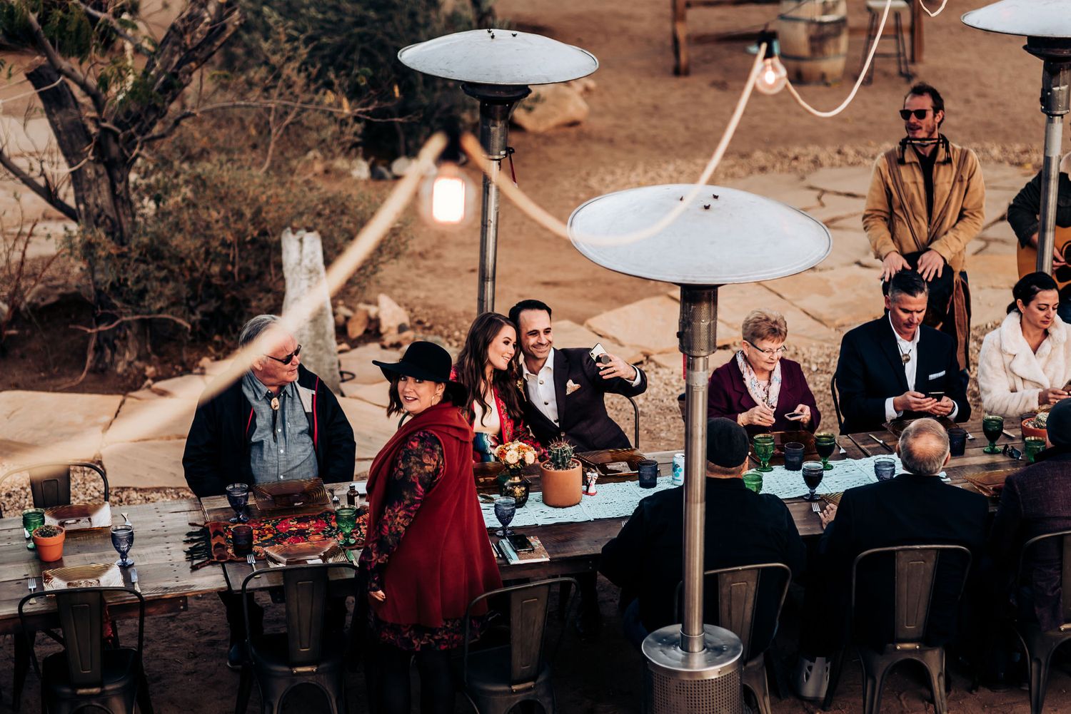 Outdoor dining setup with white umbrella heaters and desert landscape.