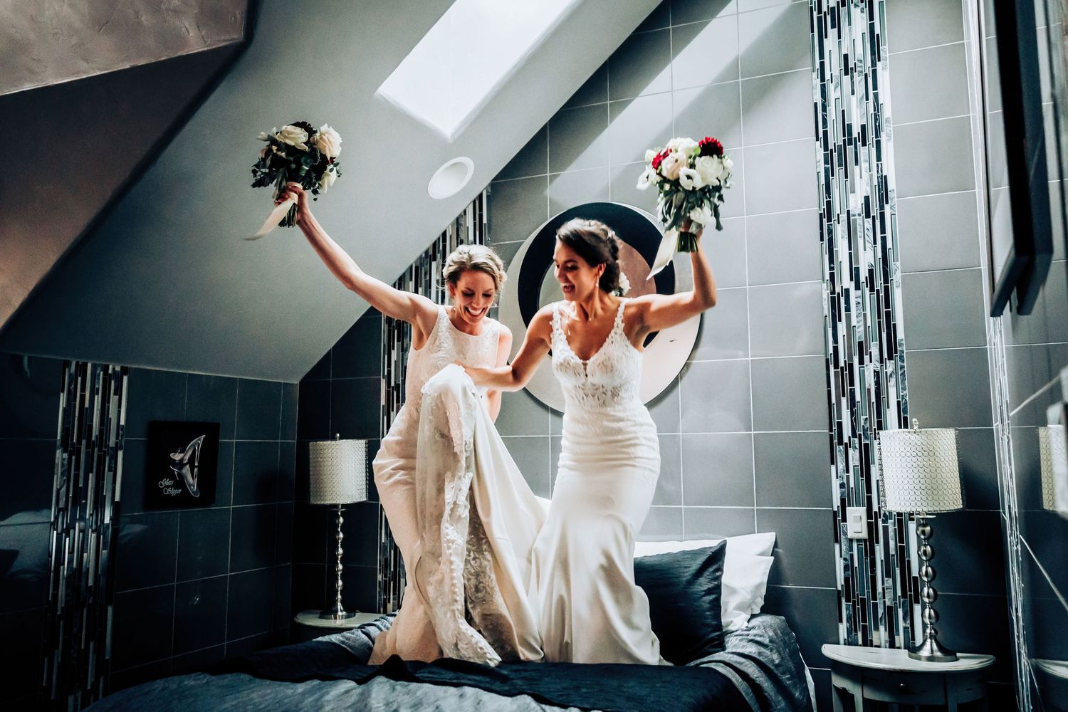 Celebratory moment captured with floating dresses and raised bouquets in modern interior setting.