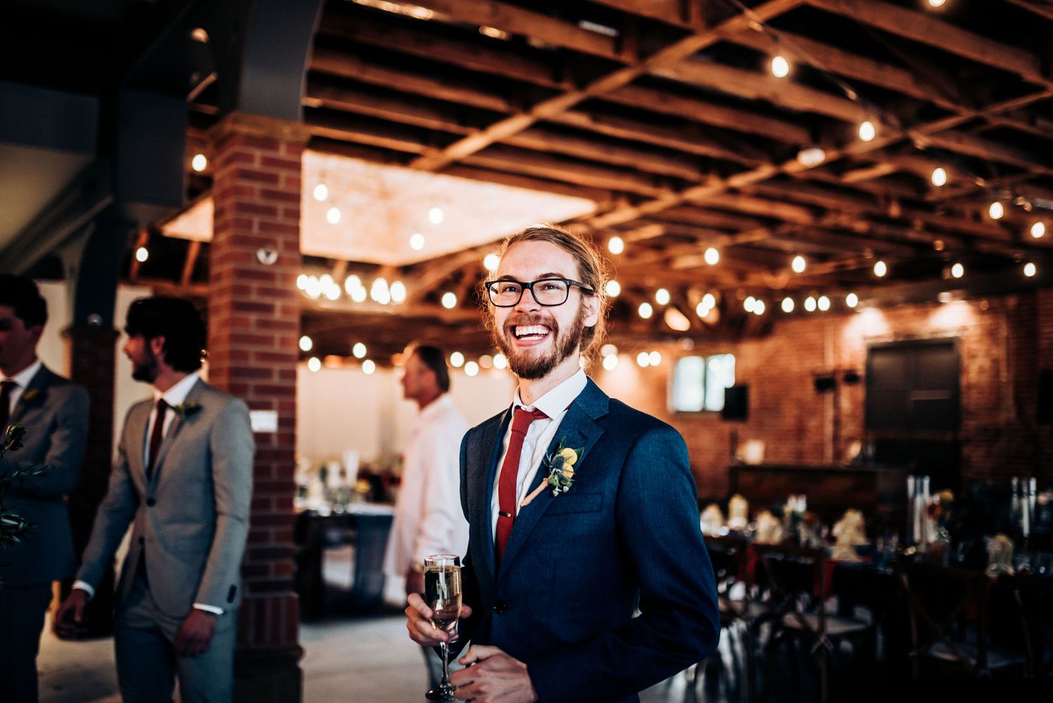 Guest enjoying reception in industrial chic venue with exposed brick and mood lighting.