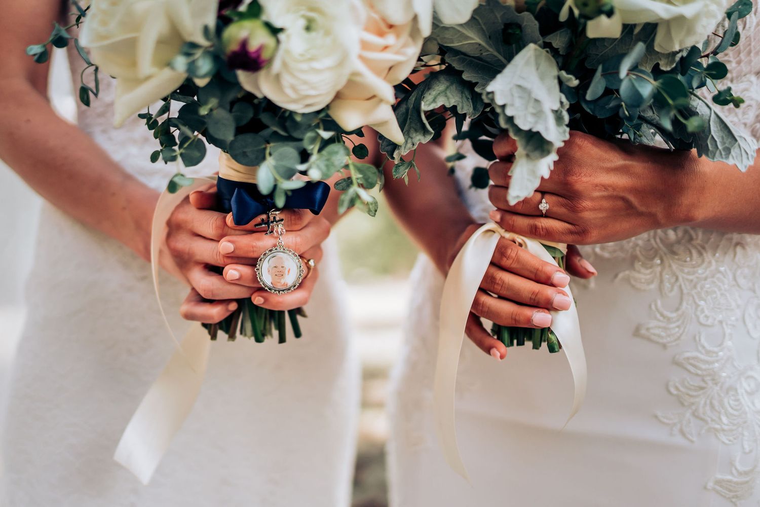 Detail shot of hands holding matching wedding bouquets with white and blush flowers.