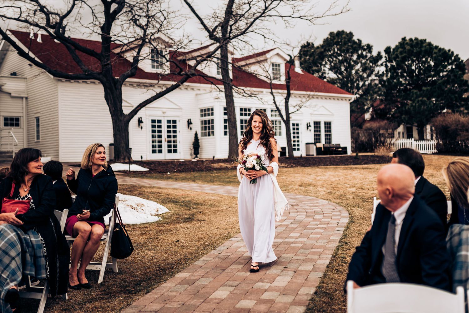 Groomsmen in formal attire stand together during outdoor wedding ceremony.