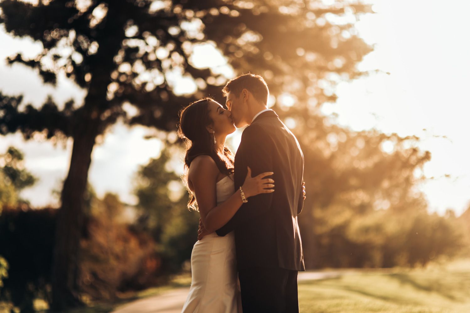 Romantic sunset portrait of couple embracing during outdoor wedding photo session.